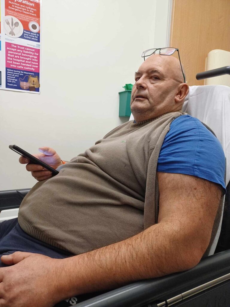 Image shows Stephen (a larger man) sitting in a chair.